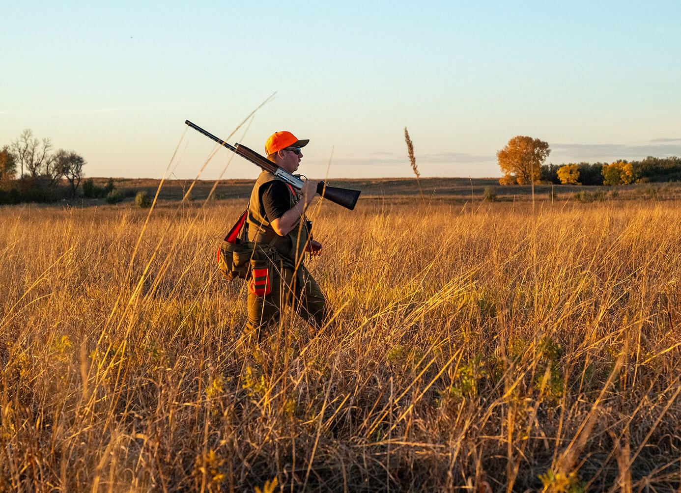 Hunter with gun walking through field
